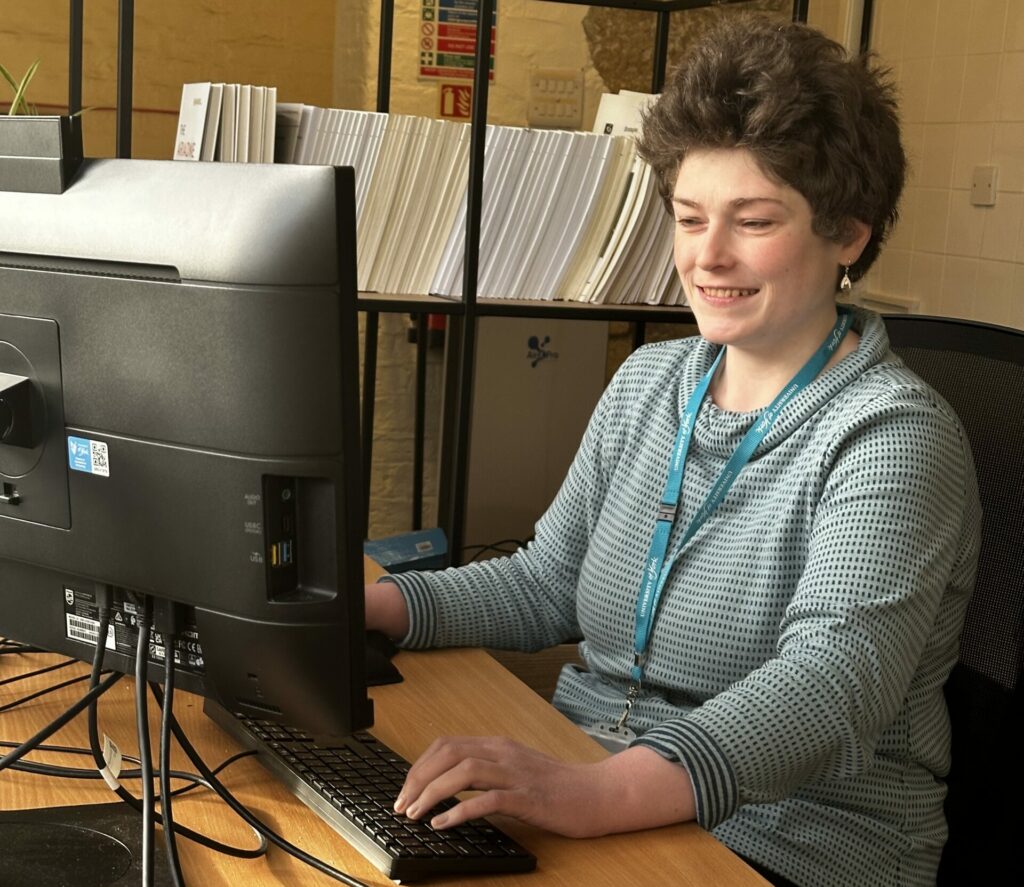 A photo of Leonora typing at her desk