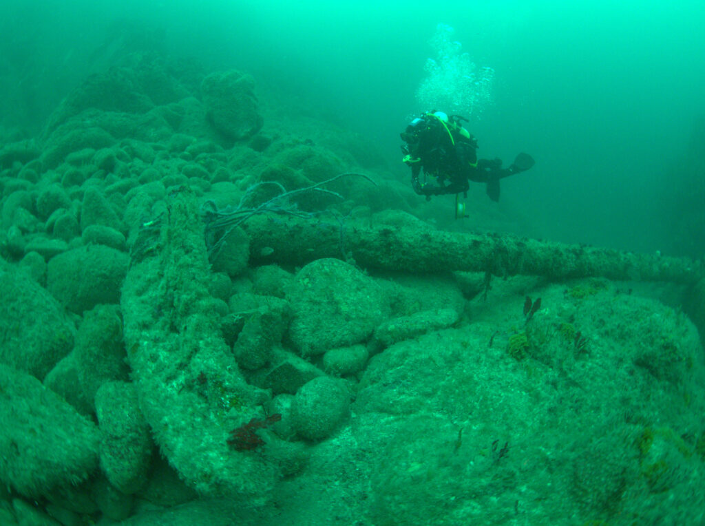 A diver is swiming toward an anchor on the ocean floor